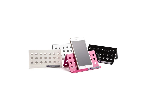 Handyhalter aus Aluminium in Pink, Silber, Weiß und Schwarz, vorn der pinke mit eingelegtem Smartphone
