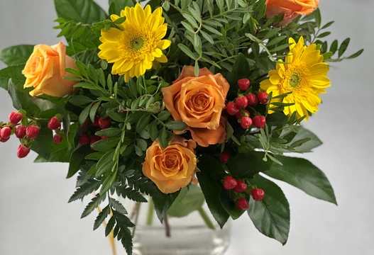 Blumenstrauß Größe M in Gelb und Orange mit Gerbera, Rosen und roten Beeren in einer Glasvase