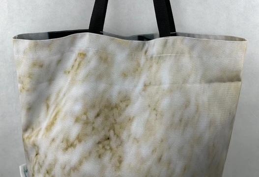 Re-Use Shopper aus Werbebannern in Cremeweiß mit hellgelber Musterung und schwarzen Henkeln