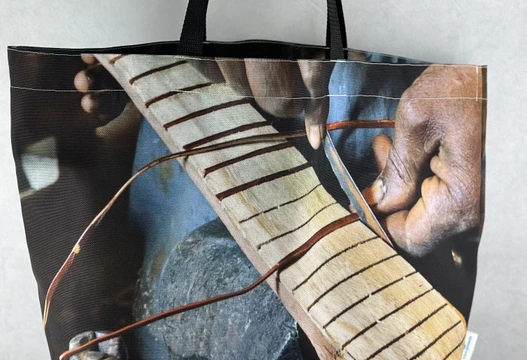 Re-Use Shopper aus Werbebannern mit Motiv einer Hand auf einem Instrumentenhals, Vorderansicht