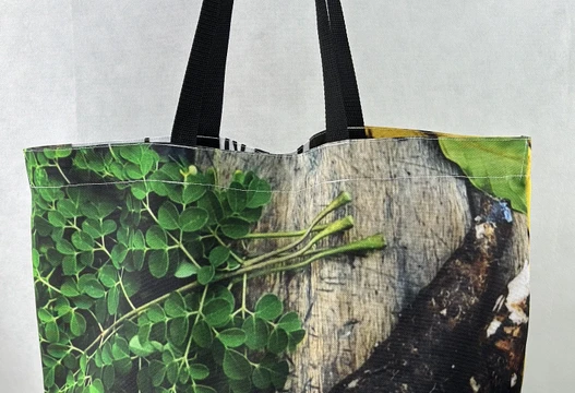 Re-Use Shopper aus Werbebannern mit grünem Blattmotiv und schwarzen Henkeln