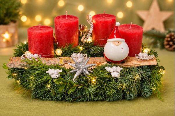 Adventskranz halbrund in Rot mit vier roten Kerzen, Tannengrün, Birkenrinde und Weihnachtsmann-Figur