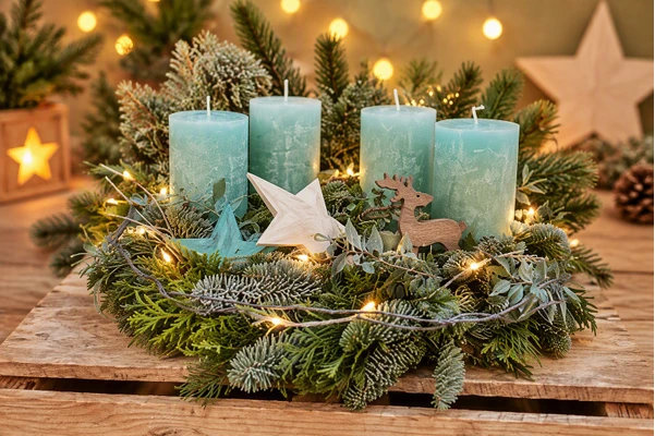 Adventskranz halbrund in Türkis mit vier Kerzen, Tannengrün, Holzstern und Rentier-Figur auf einer Holzkiste